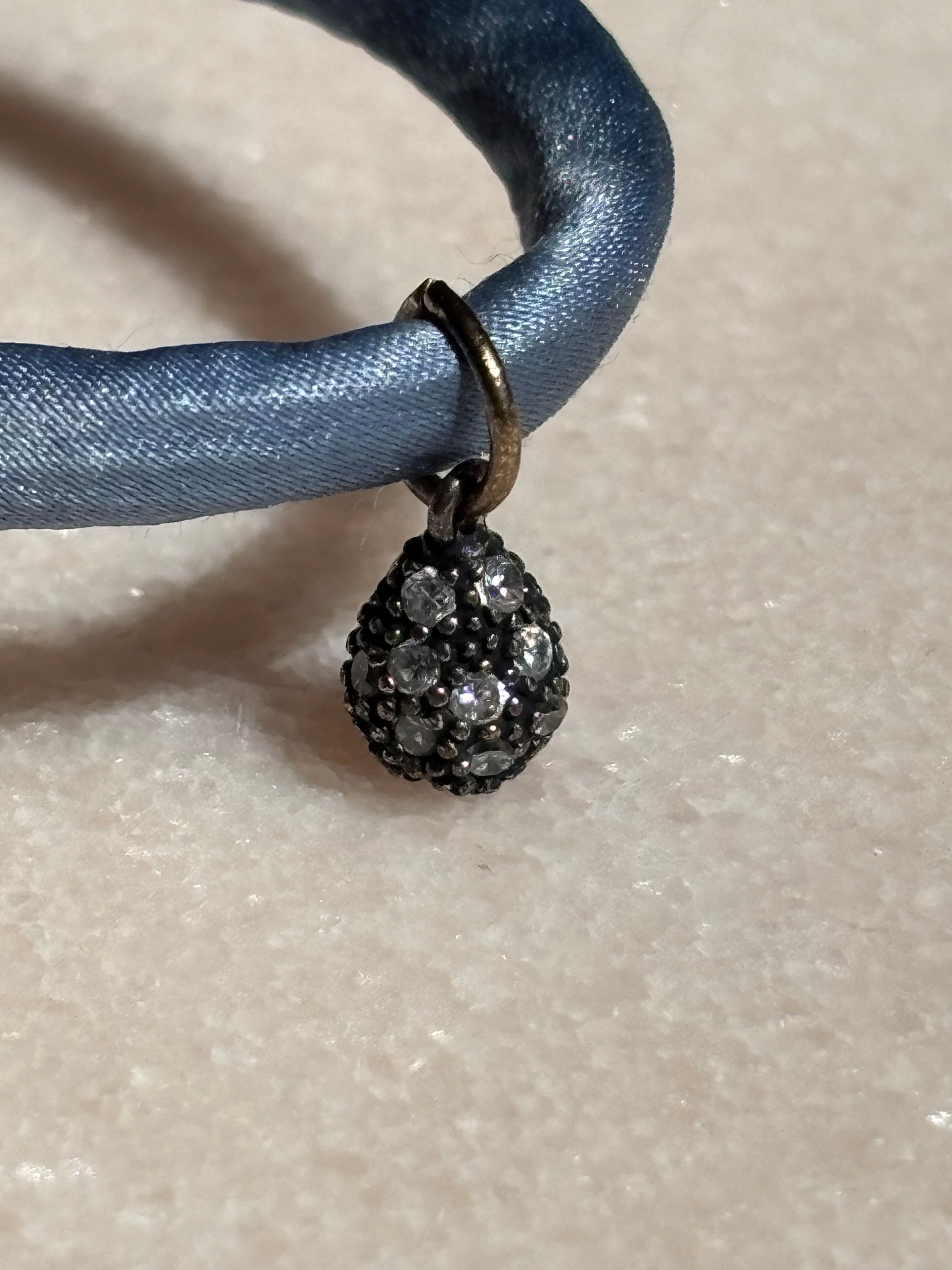 Close-up of Blue Jeans drop Silk Kiss Bracelet detailing crystal flowered eye charm and gold-filled beads by Boussidan.