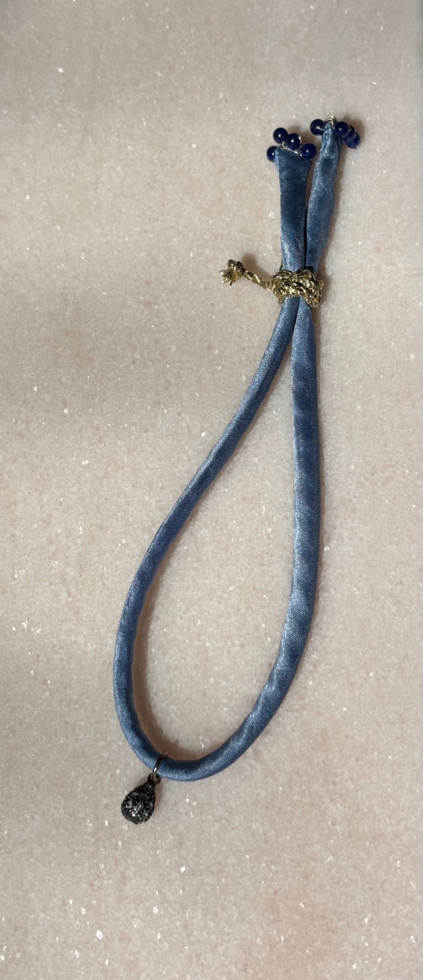 Side view of Blue Jeans Silk Kiss Bracelet showing blue jeans-colored silk cord and gold button by Boussidan.