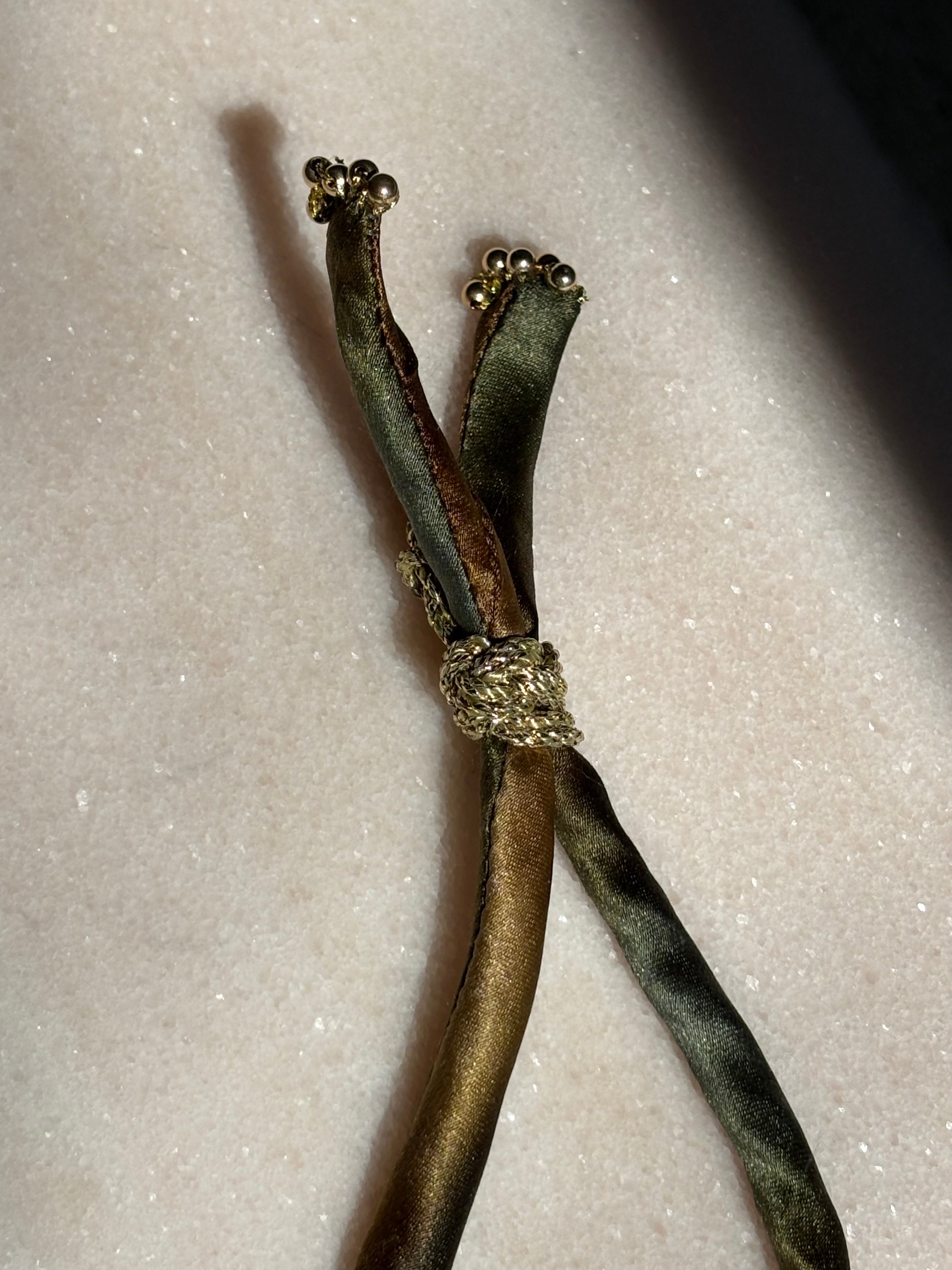 Side view of Army Gold Ombre Silk Kiss Bracelet showing army green silk cord and double gold button by Boussidan.