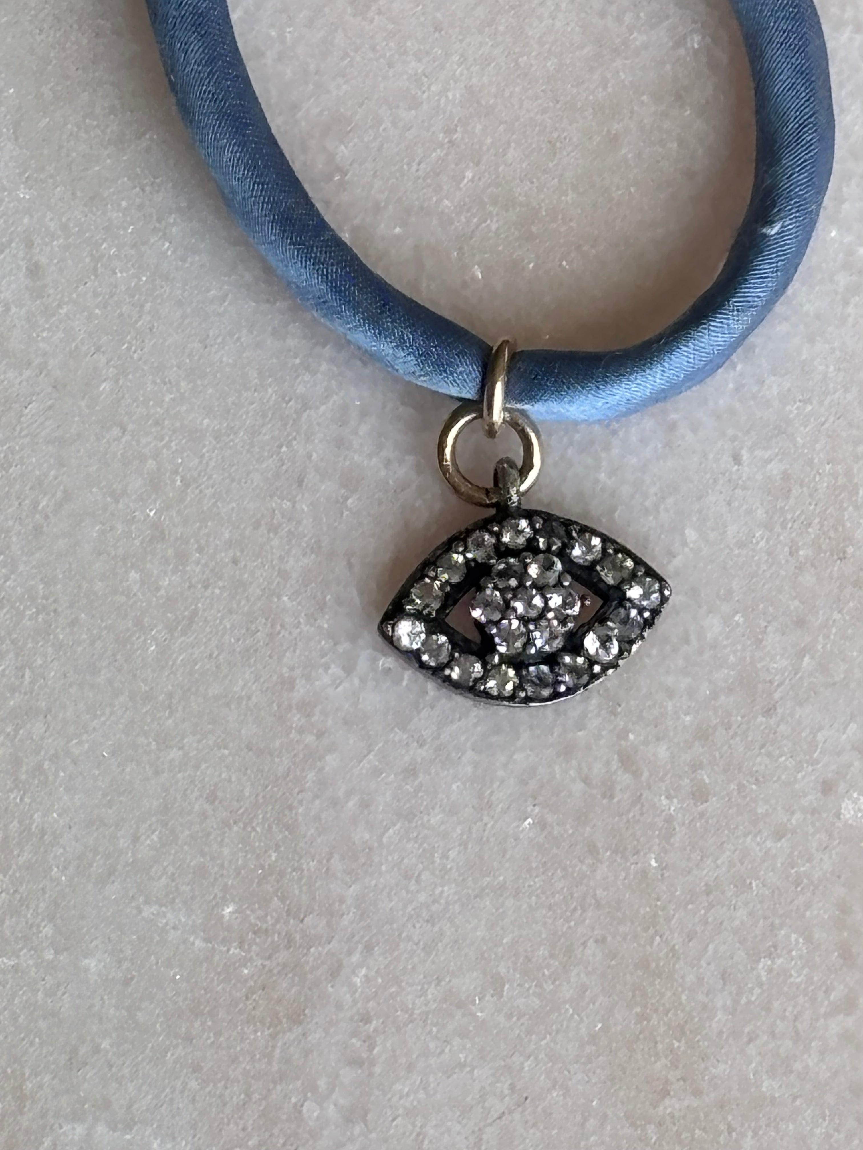 Close-up of Blue Eyed Silk Kiss Bracelet detailing crystal flowered eye charm and gold-filled beads by Boussidan.