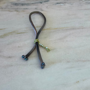 Ombre silk bracelet with black pearls, worn on wrist, showcasing gold braided button