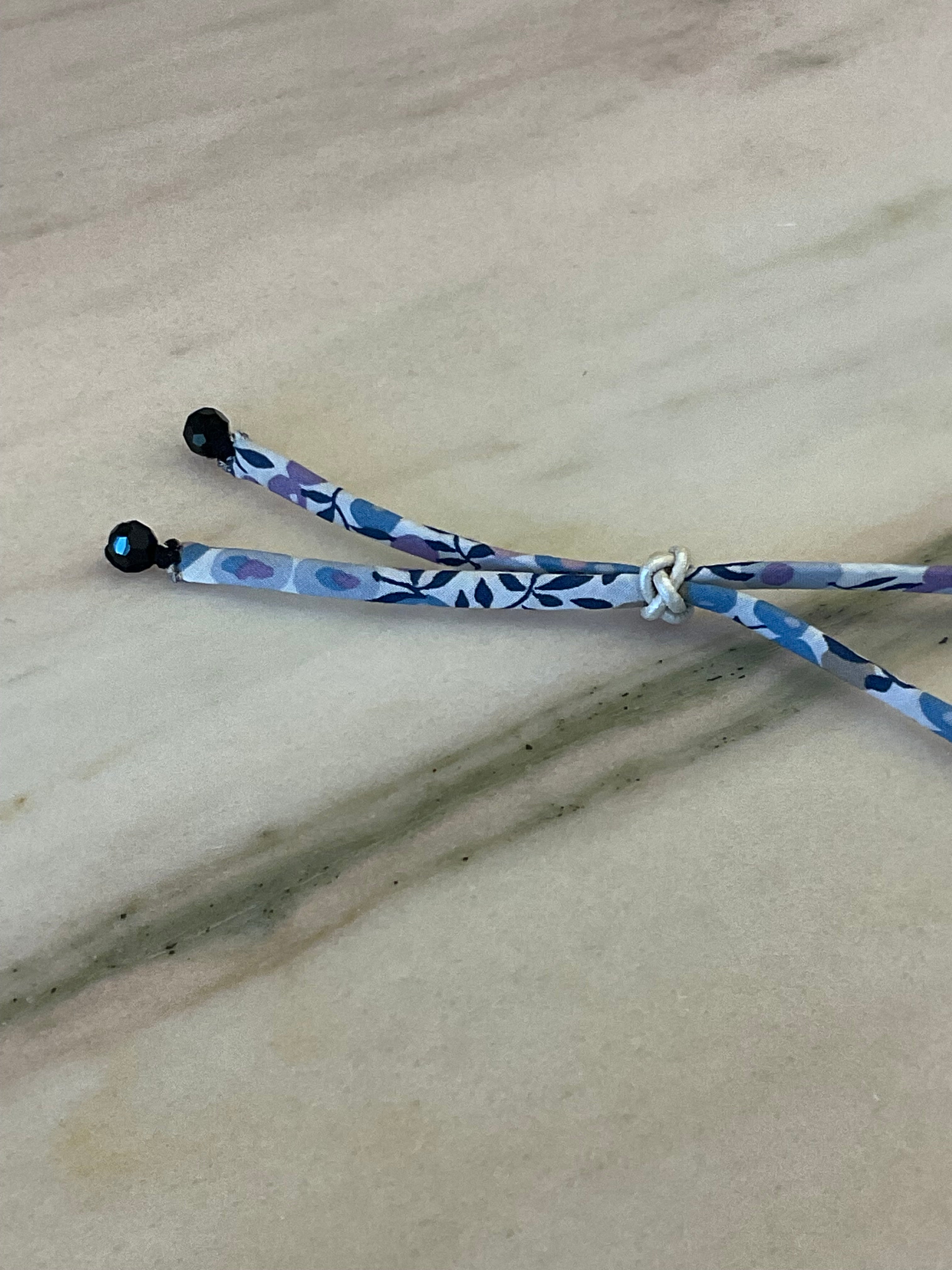Side view of Onyx Drops Wild-Flowers Liberty Bracelet showing floral cord and white leather button by Boussidan.