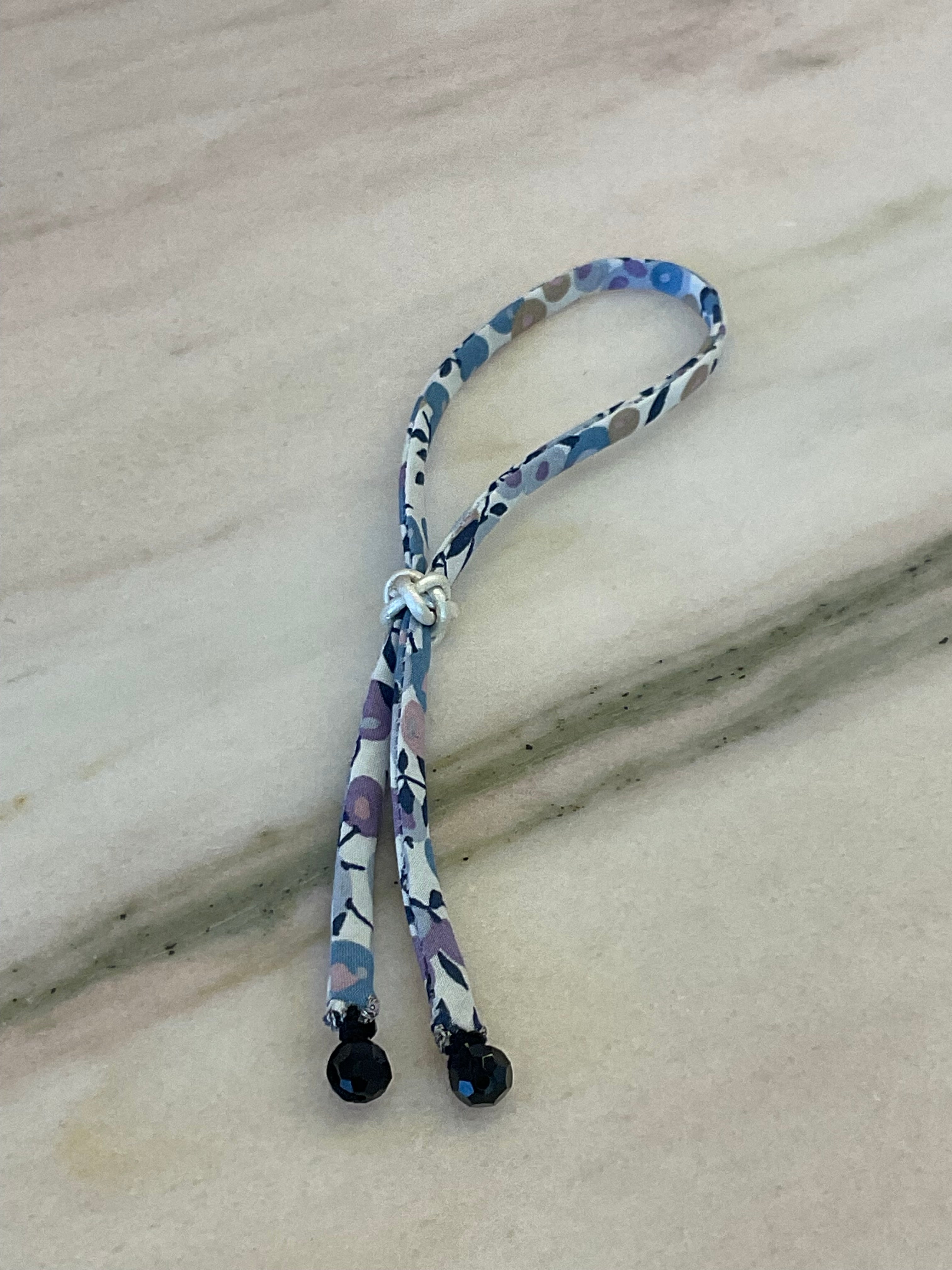 Side view of Onyx Drops Wild-Flowers Liberty Bracelet showing floral cord and white leather button by Boussidan.