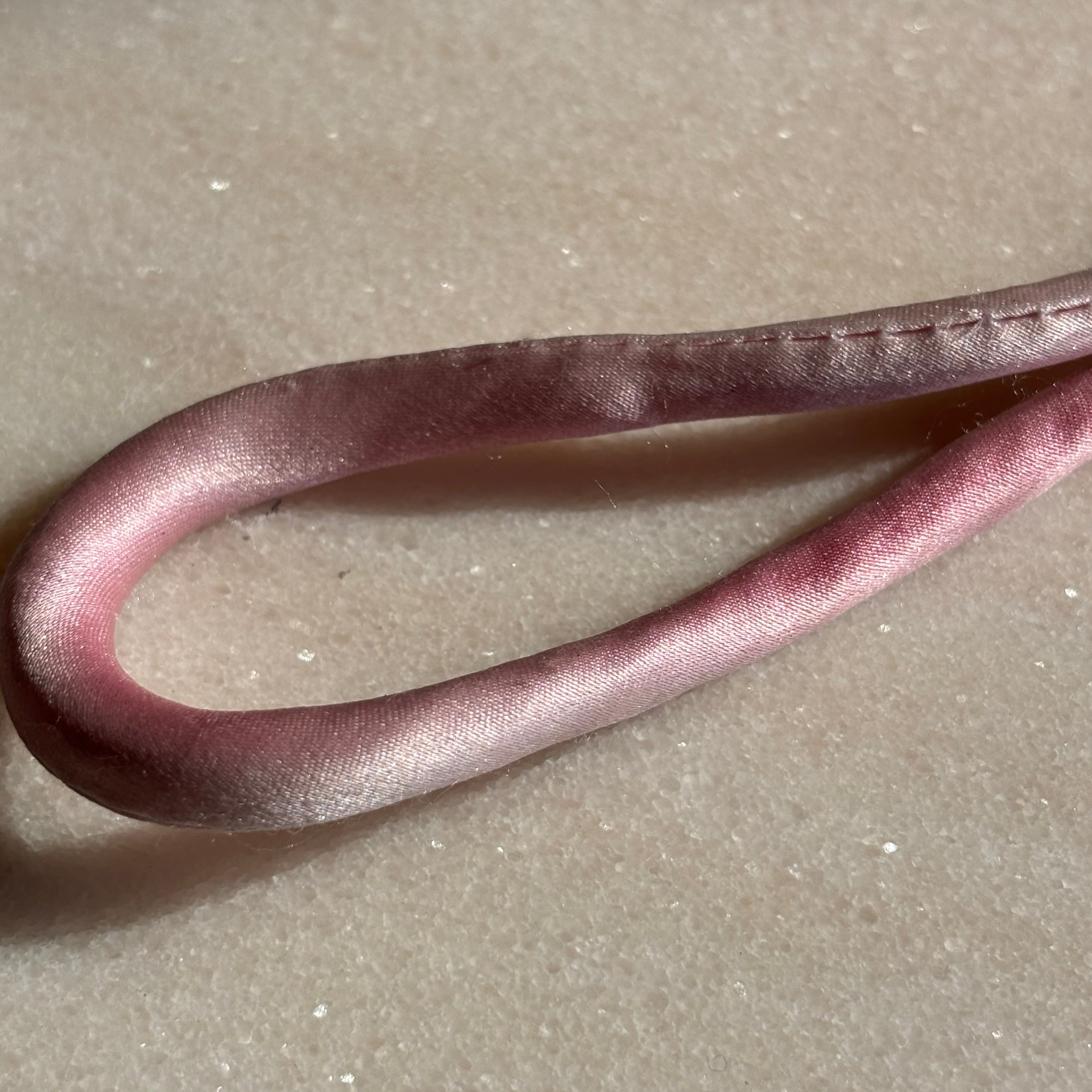 Pink silk adjustable bracelet finished with red spinel and mother of pearl clover and gold cord button slides up and down 
